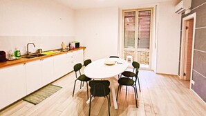 A compact kitchen with a dining table and chairs, a window with blinds, and a door leading to a balcony. - Crispi Penthouse at historic center with panoramic terrace  (Catania)