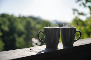 Deux tasses posées sur une étagère en bois, avec un arrière-plan flou de couleur verte.