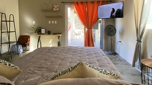 Ein Schlafzimmer mit einem Bett, einem Fernseher an der Wand, einem Schreibtisch und einem Sessel.