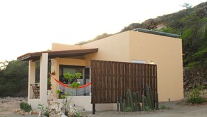 Ein modernes Haus mit Holzzaun, Kakteen und einer Hängematte.