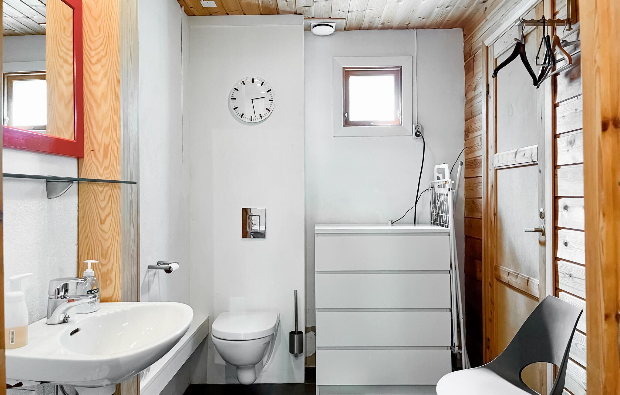 A compact bathroom with a white sink, toilet, and a small window.
