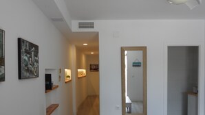 Un couloir moderne et bien éclairé, doté d’un plancher en bois, qui mène à une salle de bain au sol décoré de motifs.