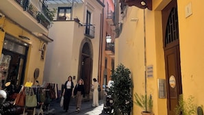 A narrow cobblestone street with buildings on either side, a few pedestrians, and outdoor seating areas. - Apartment in the heart of Sorrento (Sorrento)