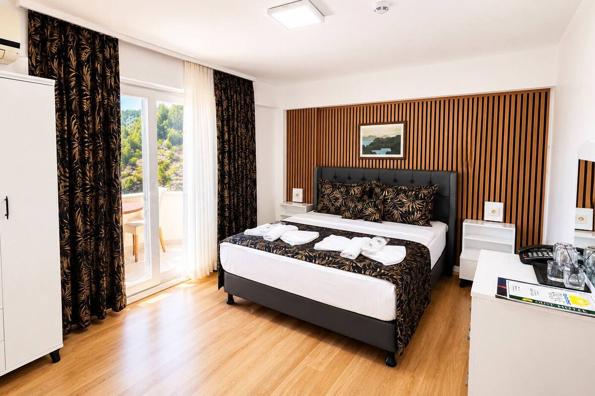 A hotel room with a bed, a wardrobe, a desk, and a view of the outdoors.