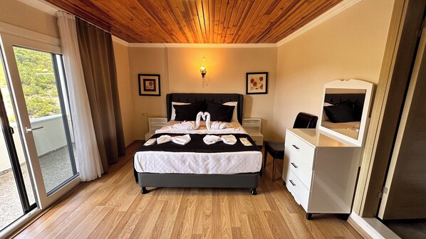 A hotel room with a wooden ceiling, a bed with towels arranged in a swan shape, a dresser, and a mirror. - Olive Branch Hotel (Ayvalik)