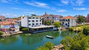 A riverside hotel with a boat dock, multiple balconies, and a view of the river. - Olive Branch Hotel (Ayvalik)