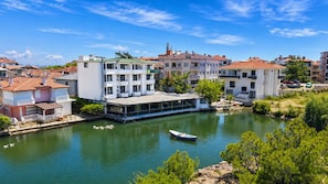 A riverside hotel with a boat dock, multiple balconies, and a view of the river. - Olive Branch Hotel (Ayvalik)