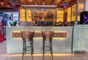 A bar area with a sign reading 'OLYMPIAN BRAND HOTEL' and two bar stools. - Olive Branch Hotel (Ayvalik)