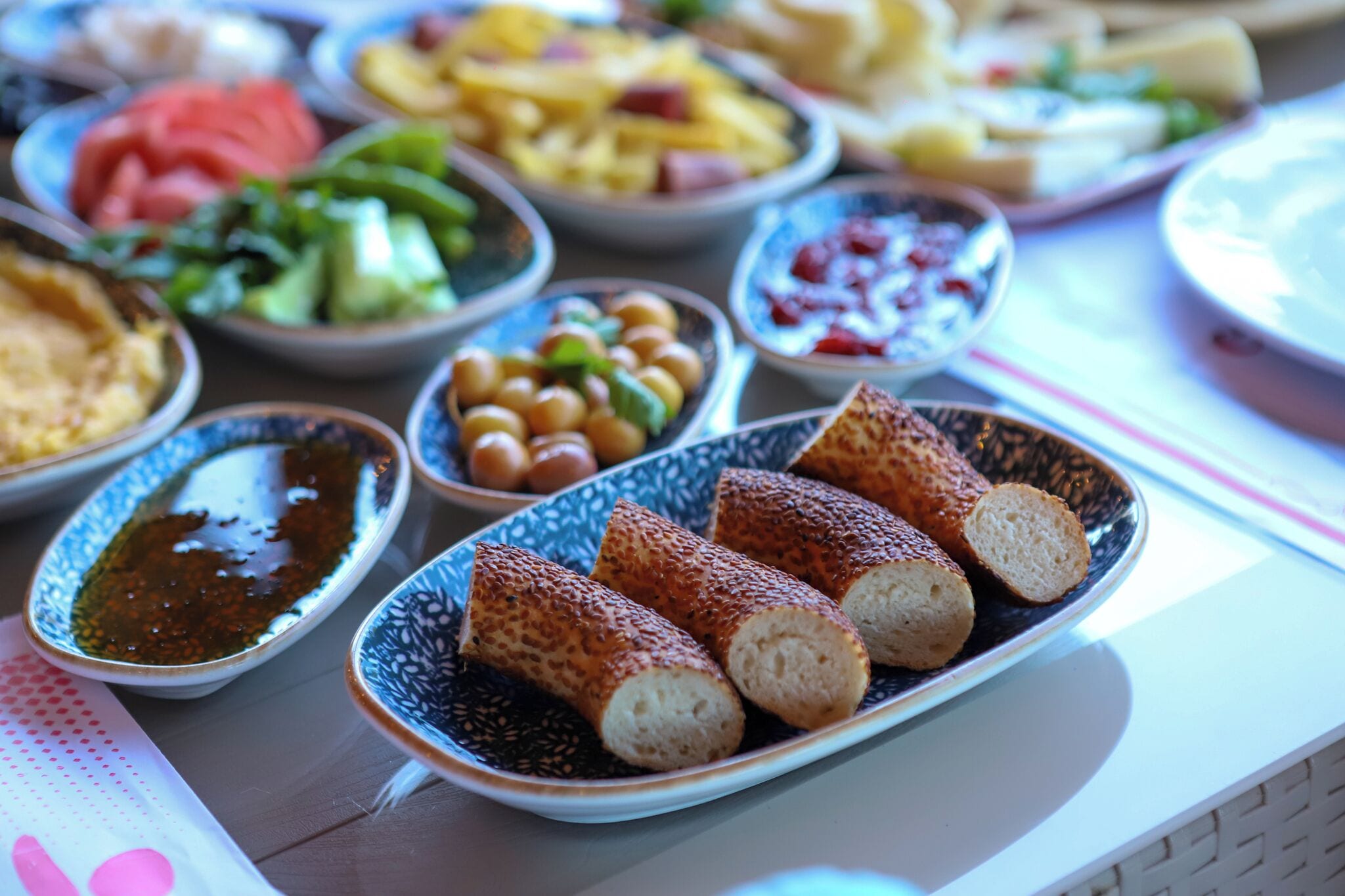 Una mesa con diferentes platos, incluyendo panes, aceitunas y salsas.