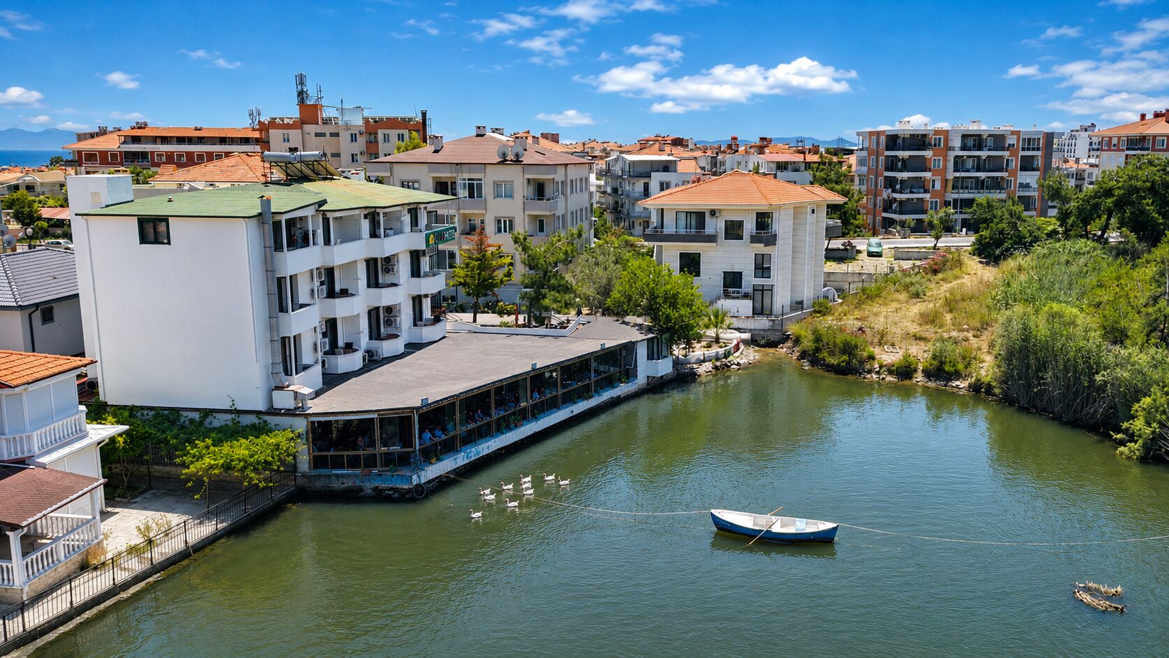 Hotel junto al río con un muelle para barcos, varios balcones y vistas al río.