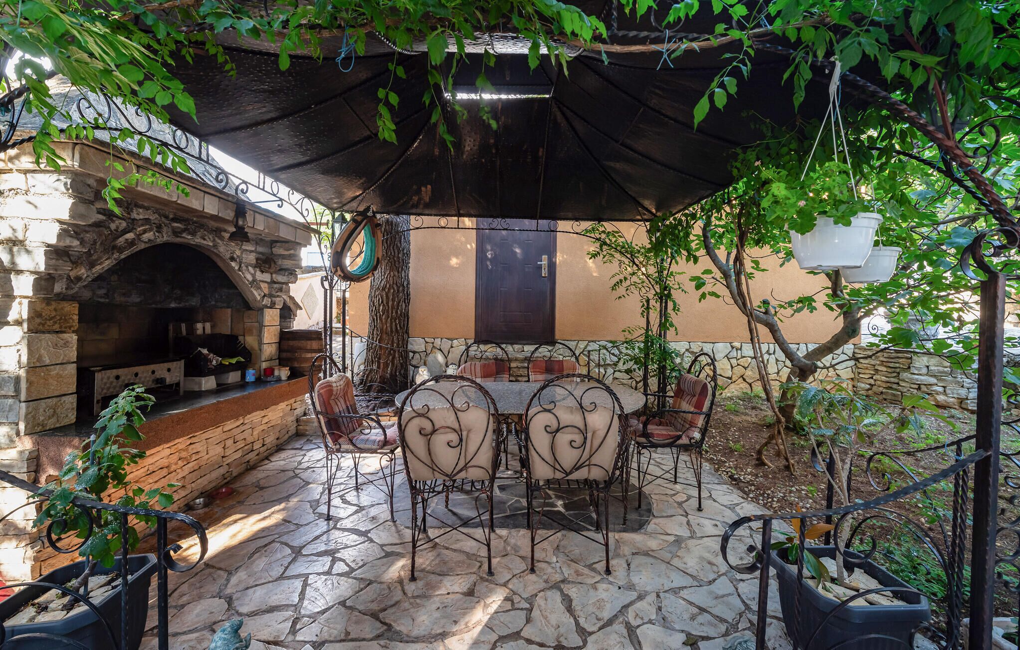 An outdoor patio with stone flooring, a stone fireplace, and metal chairs.
