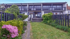 A two-story building with a covered outdoor seating area and a stone pathway leading to the entrance.