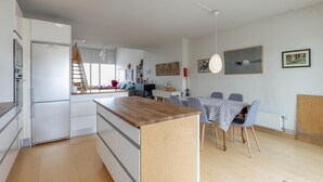 A modern kitchen with white cabinetry, a wooden island, and a dining area with a table and chairs.