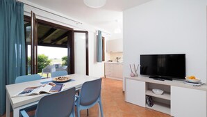Een moderne keuken met een eetgedeelte, een televisie en uitzicht op de omgeving.