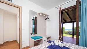 Een slaapkamer met een bed, een spiegel, een klein bankje en uitzicht op de omgeving.