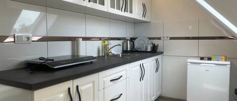 Una cocina moderna con armarios blancos, encimera negra y lavavajillas integrado.