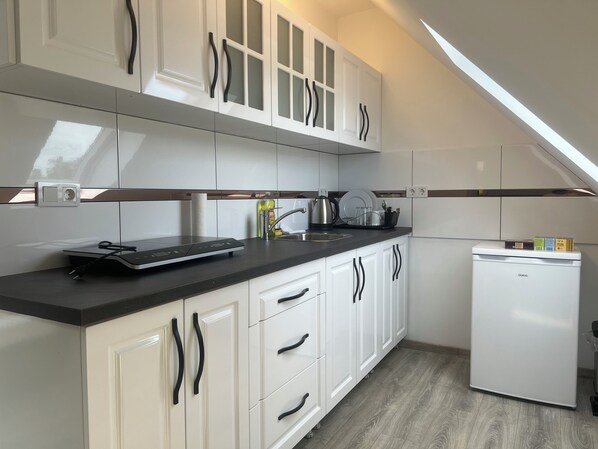 A modern kitchen with white cabinets, a black countertop, and a built-in dishwasher. - Durmaz Hotel (Hannover)