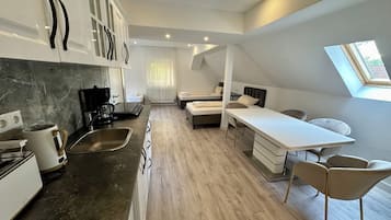 A modern kitchen with a coffee maker, sink, and a dining area with a table and chairs.