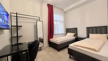 A hotel room with two beds, a desk, a chair, a TV, and a mirror.