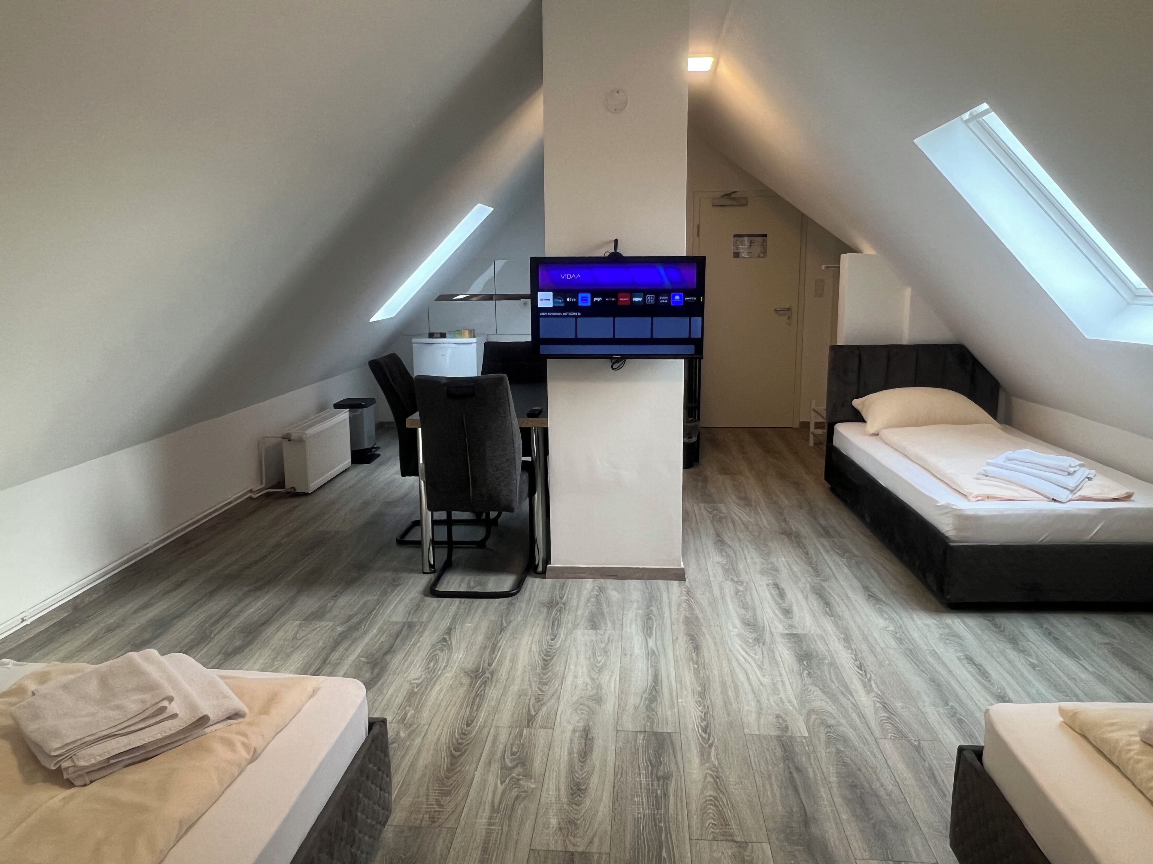 A compact room with a desk, a bed, and a small kitchenette.