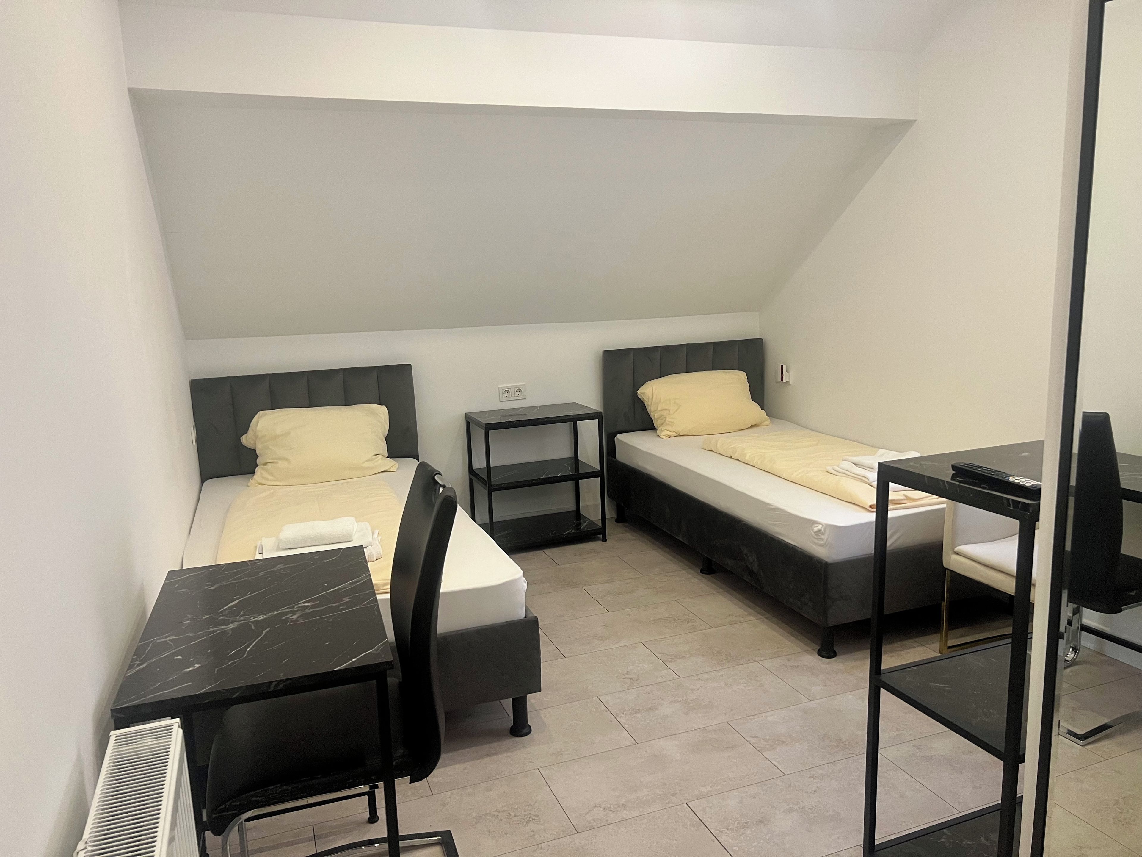 A compact room with two beds, a desk, and a chair.