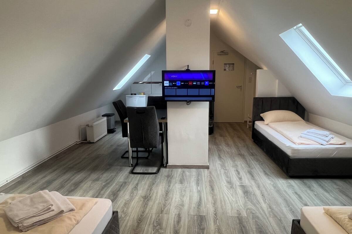 A compact room with a desk, a bed, and a small kitchenette.