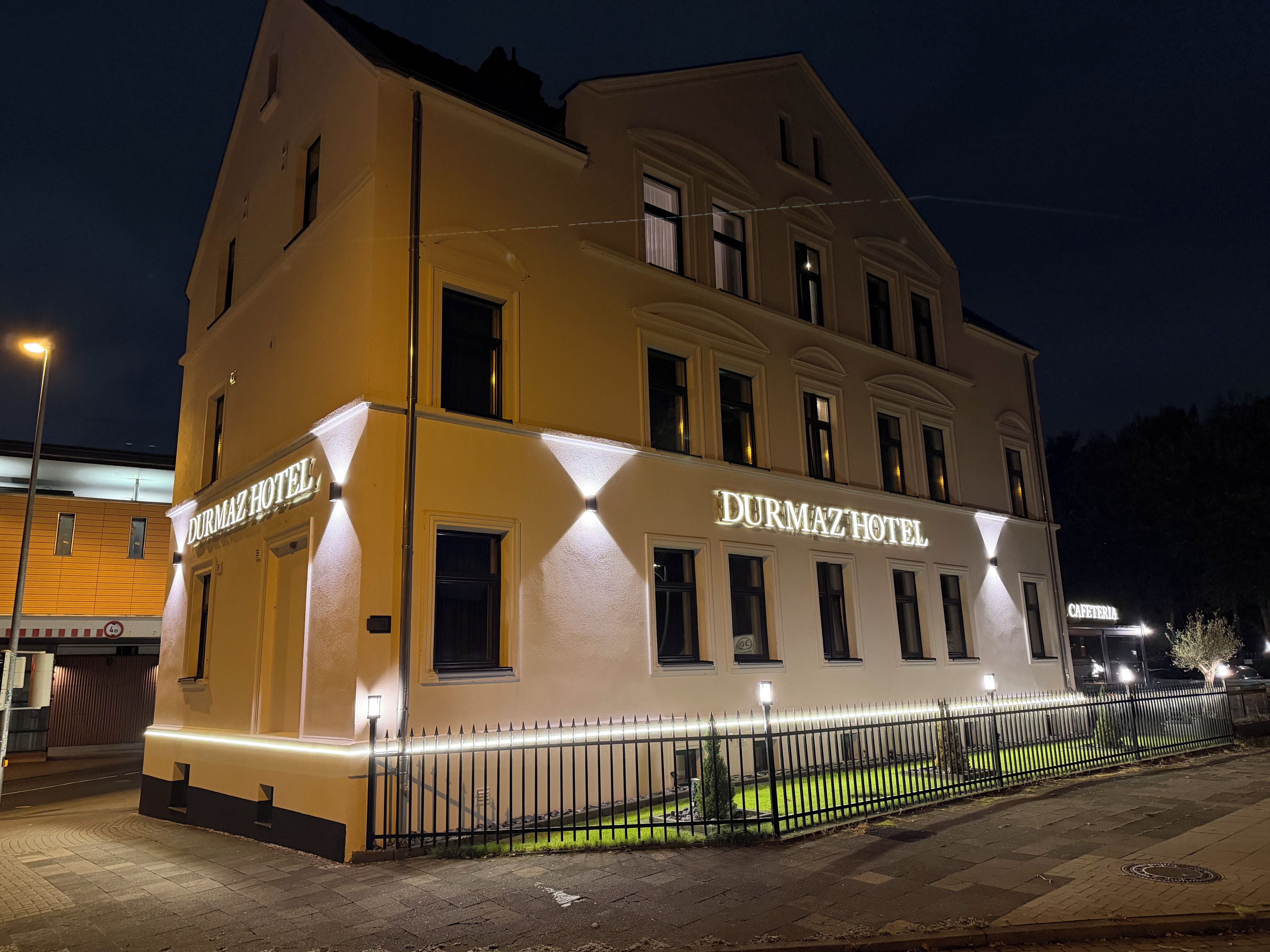 Un hotel con un letrero llamativo, una fachada bien iluminada y un acceso mediante portón.