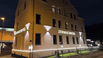 Un hotel con un letrero llamativo, una fachada bien iluminada y un acceso mediante portón.