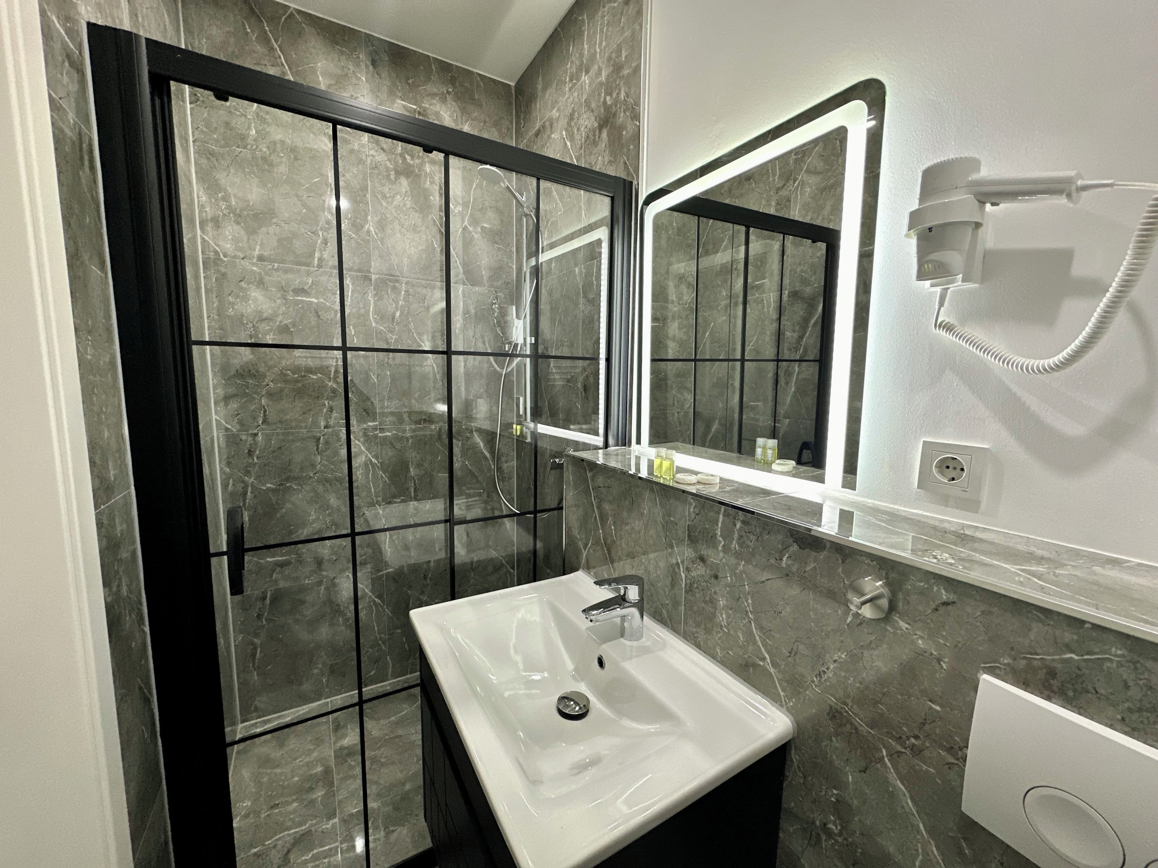 Ein Badezimmer mit Dusche, Waschbecken und Spiegel.
