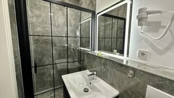 Ein Badezimmer mit Dusche, Waschbecken und Spiegel.