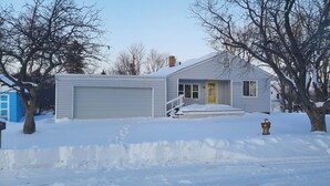 A single-story house with a garage, a front porch, and a yellow door.