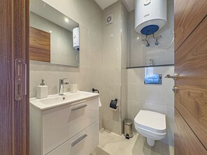Un baño moderno con tocador, lavabo, espejo y un área de inodoros separada.