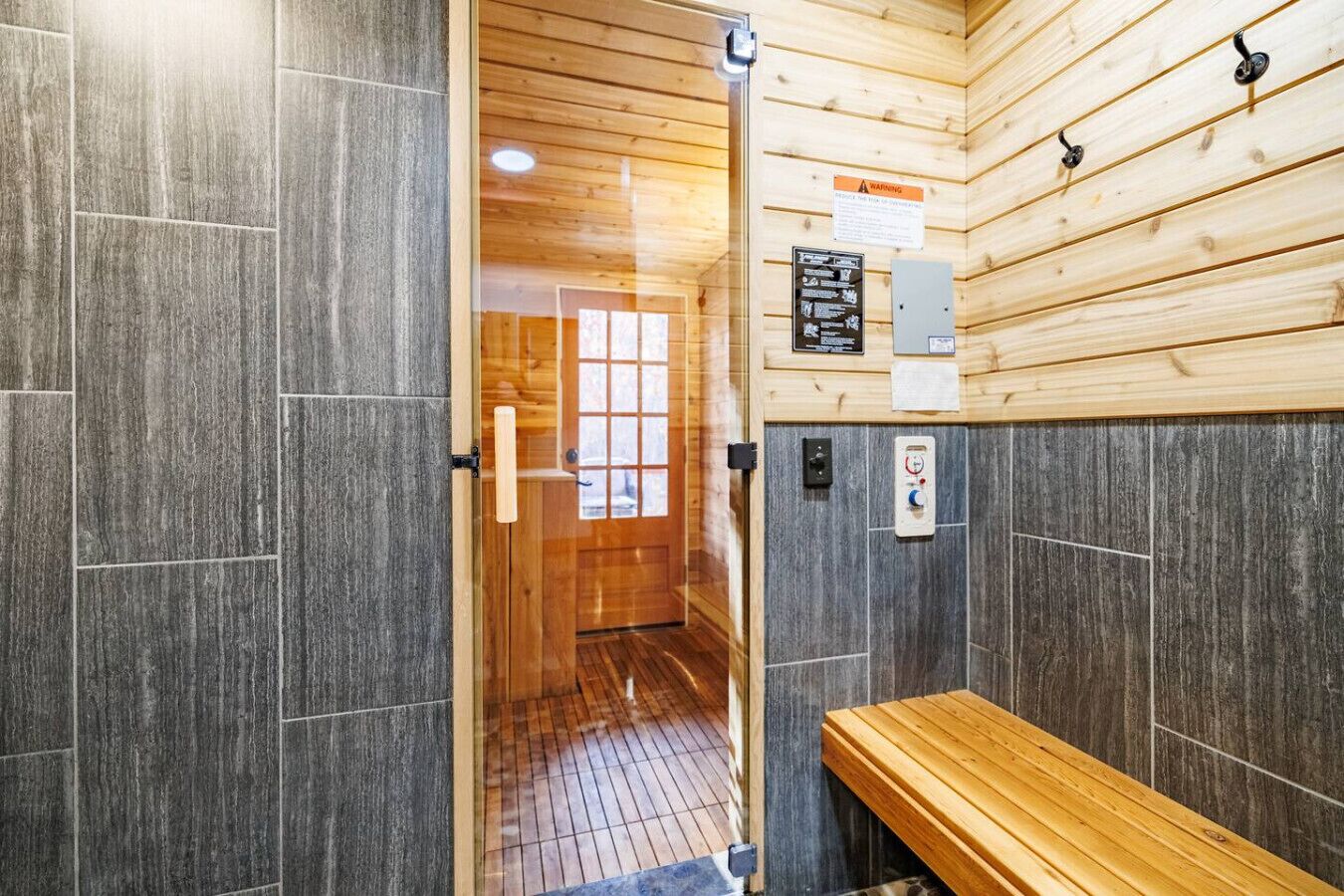 Un sauna con paredes de madera, un banco y una puerta que da a otra zona.