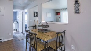 A dining area with a wooden table and four chairs, a metal tray, and a mirror on the wall. - Jelinek Hideaway Unit 1 - Modern 2BR Apartment (Wasusau)