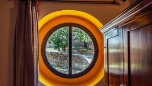 A room with a circular window overlooking a stone wall and greenery. - Lovely apartment in Castiglione d'Orcia (Castiglione d'Orcia)