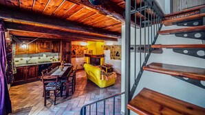 A rustic interior with a wooden staircase, a dining area with a yellow table, and a stone fireplace. - Lovely apartment in Castiglione d'Orcia (Castiglione d'Orcia)