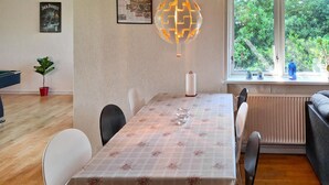 Un coin repas avec une table dressée pour quatre personnes, un luminaire en forme de globe et une fenêtre donnant sur un paysage verdoyant.