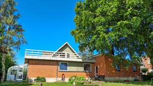 Un bâtiment de deux étages en briques, doté d’un balcon blanc et d’une serre en verre.