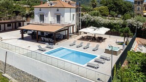 Un edificio a due piani con piscina, area relax all'aperto e vista sul paesaggio circostante.