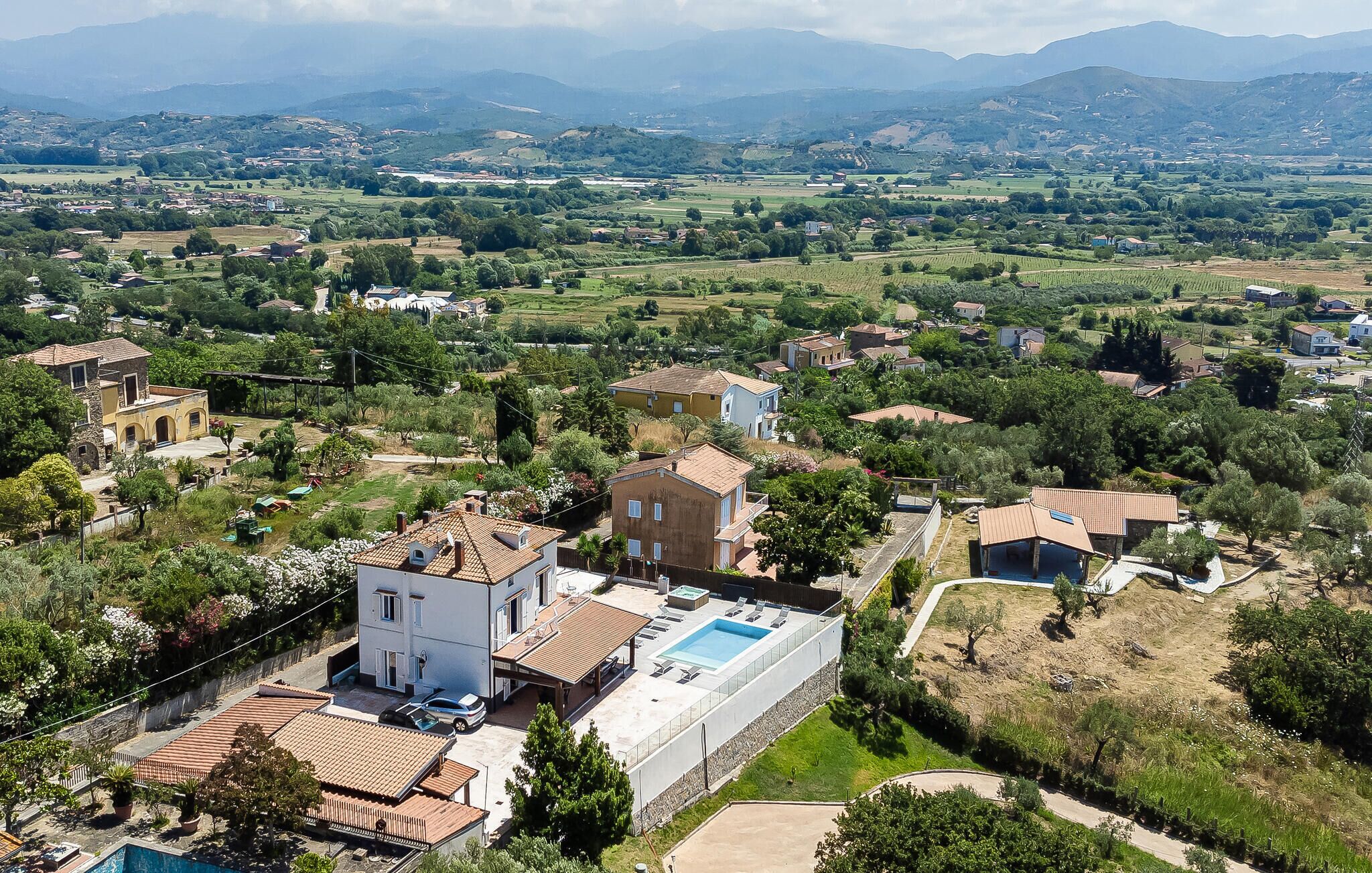 A residential area with houses, a swimming pool, and a view of the surrounding countryside.