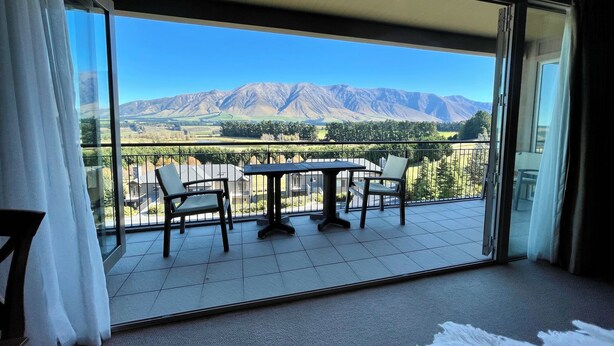 Un balcone con tavolo e sedie, che offre vista su montagne e una valle.