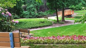 Un parc avec des bancs, un pont en bois et un étang.