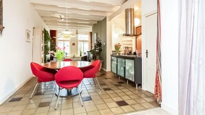 A dining area with a round table and red chairs, a kitchen with a stove and cabinets, and a tiled floor. - Lovely home in Sneek with WiFi (Sneek)