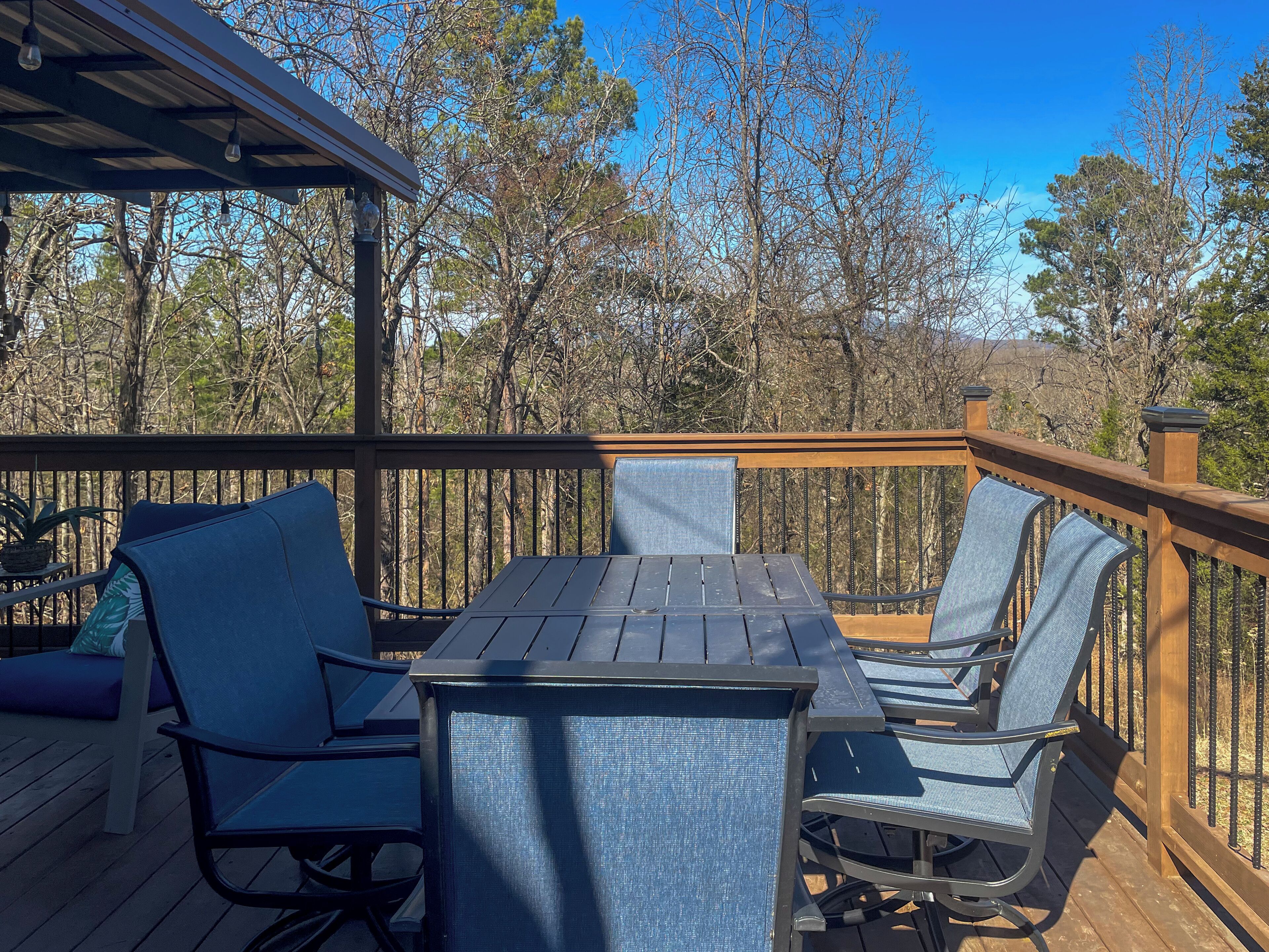 A wooden deck with a table and chairs, surrounded by trees.