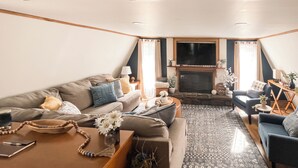 A cozy living room with a sofa, a coffee table, and a fireplace. - Cozy Wister Ridge A-Frame Lake Cabin • Sleeps 6 • Mins to Wister Lake! (Wister)