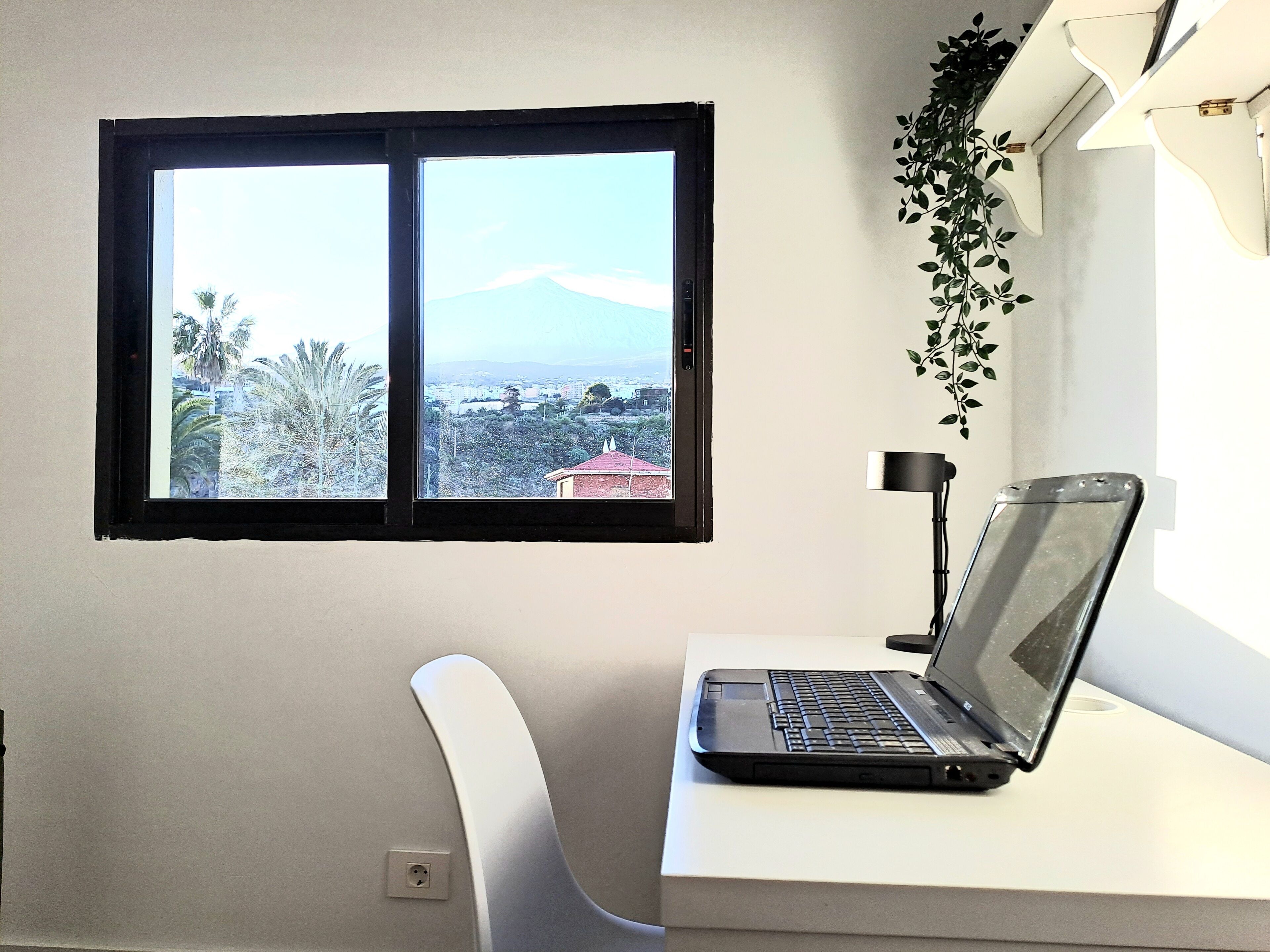 Una laptop sobre un escritorio con vista a un paisaje urbano y una montaña.