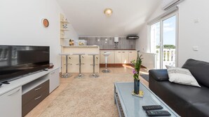 Un salon moderne avec un téléviseur, un canapé, une table basse et un balcon offrant une vue agréable.