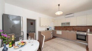 Une cuisine moderne avec un coin repas, comprenant une table ronde, des chaises, un réfrigérateur, un four à micro-ondes, une cuisinière et un distributeur d’eau.