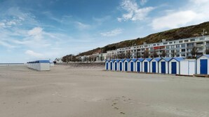 A beach with a row of blue and white beach huts, a sandy beach, and a row of buildings in the background. - Beautiful home in Bezinghem with WiFi (Bezinghem)