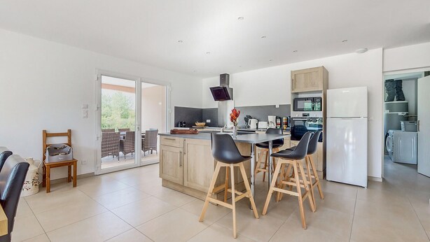 A modern kitchen with a central island, bar stools, and a dining area with a table and chairs. - Beautiful home in Bezinghem with WiFi (Bezinghem)